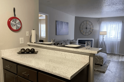 A kitchen with a white countertop and a clock hanging on the wall.
