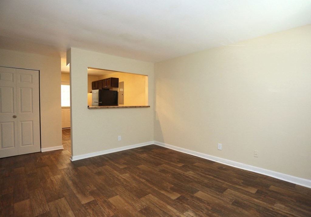 an empty living room with wood flooring and a mirror on the wall