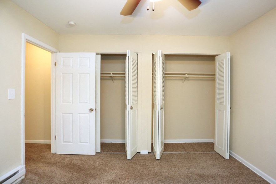 a bedroom with three closets and a ceiling fan