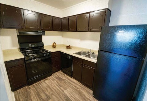 A kitchen with dark brown cabinets and a black refrigerator.