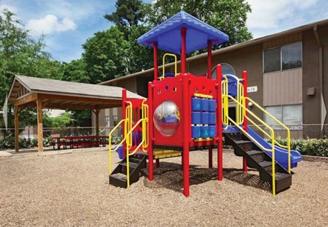 A playground with a red and blue slide and a yellow railing.