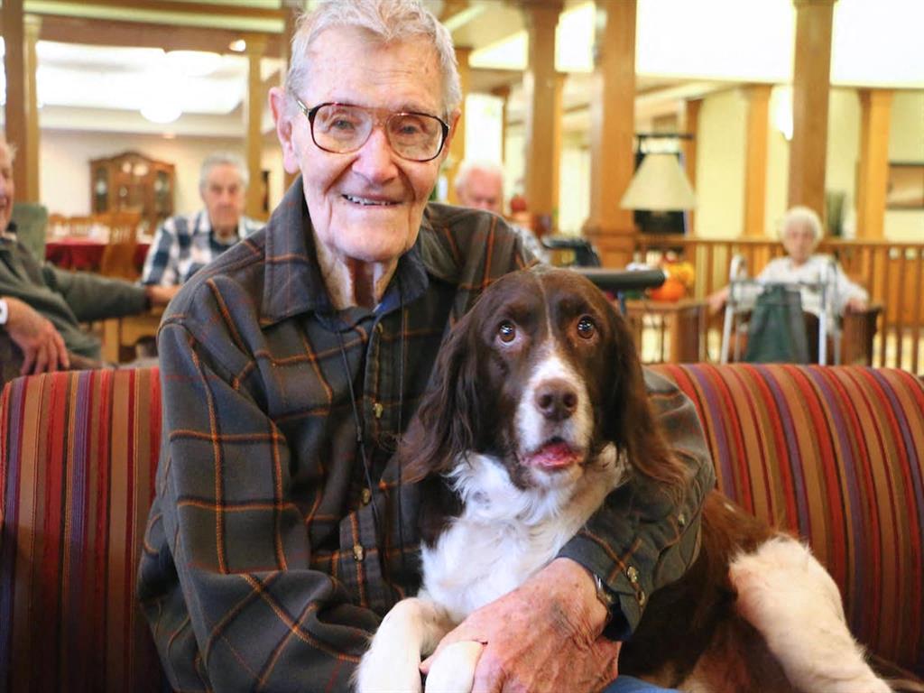 Symphony resident smiling with his pet dog