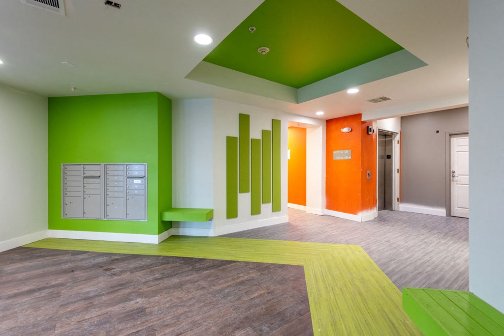 Lobby with community mail boxes and bright green and orange painted walls, bright green bench, wood like flooring