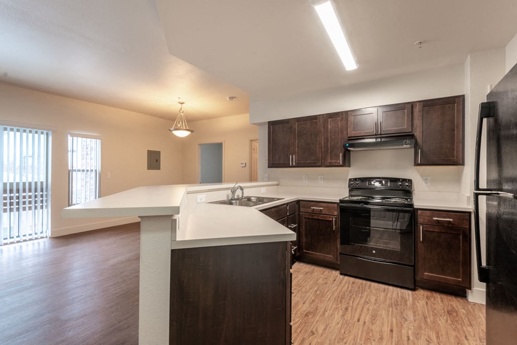 Kitchen with dark brown cabinets, black appliances, grey countertops