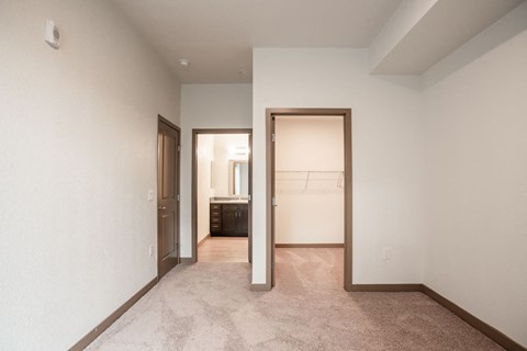 the living room and bedroom of a house with white walls and carpet