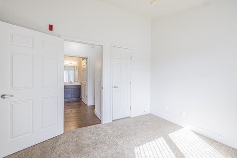 A bedroom with carpet and view towards ensuite bathroom