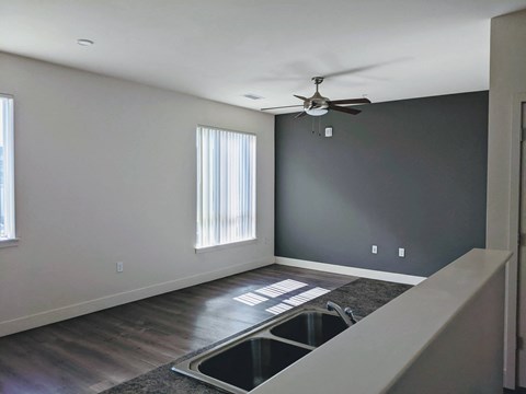 an empty living room with a kitchen sink and a ceiling fan