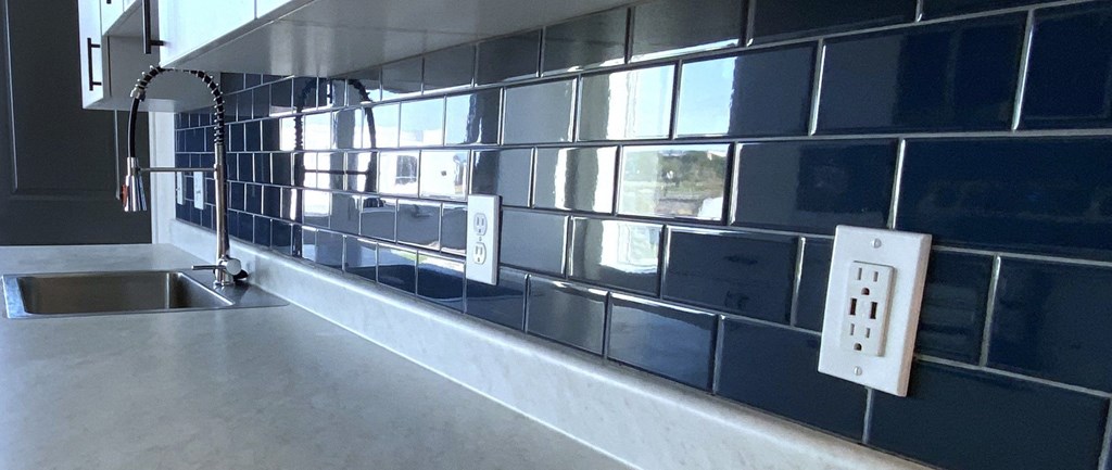 a black tiled kitchen with a sink and a window