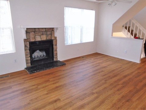 an empty living room with a fireplace and wooden floors