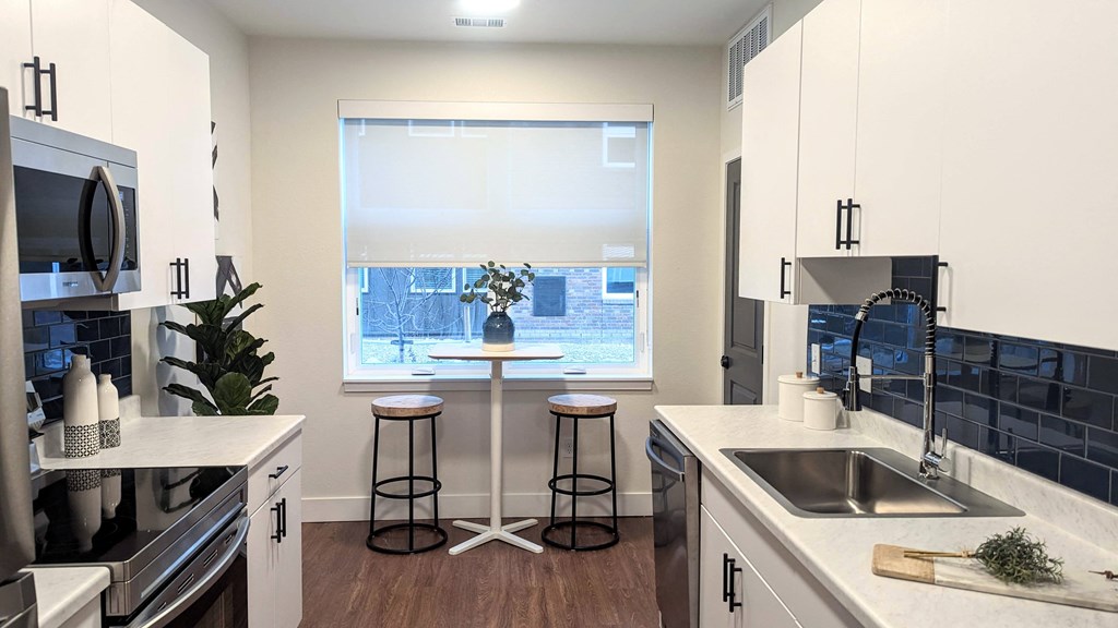 a kitchen with a window and a sink and a table with stools