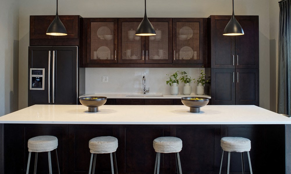 four barstools under a large kitchen island with storage in the bacl
