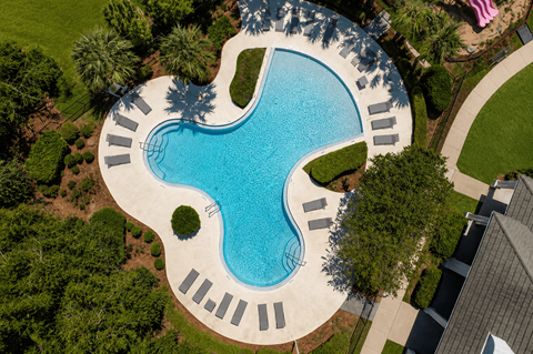 A swimming pool surrounded by trees and a concrete patio.