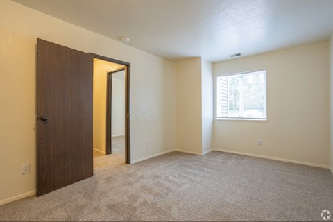 A room with a carpeted floor, a door, and a window.