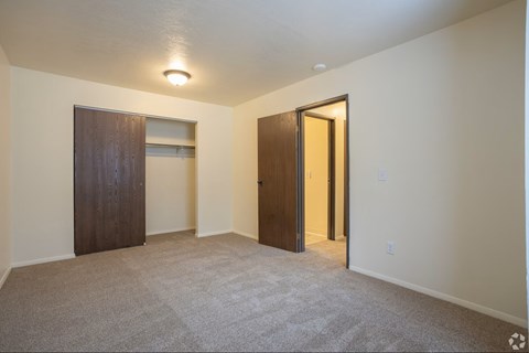 A room with a carpeted floor and two doors, one of which is open.