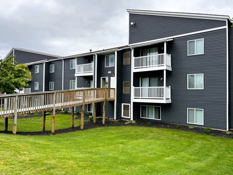 A large grey apartment building with a wooden deck in front.