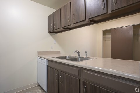 A kitchen with brown cabinets and a white dishwasher.