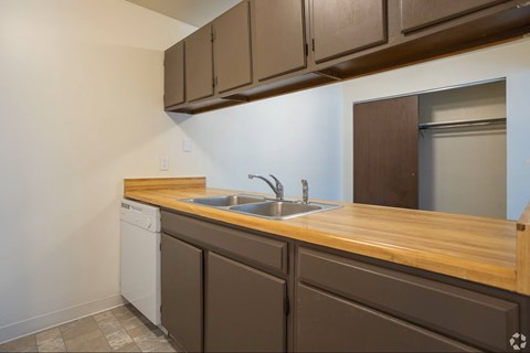 A kitchen with brown cabinets and a white dishwasher.