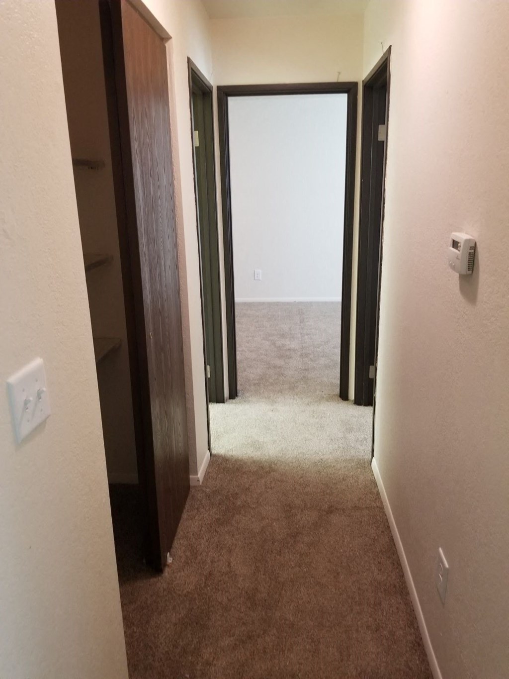 a hallway with two doors and a carpeted floor and an open door to a