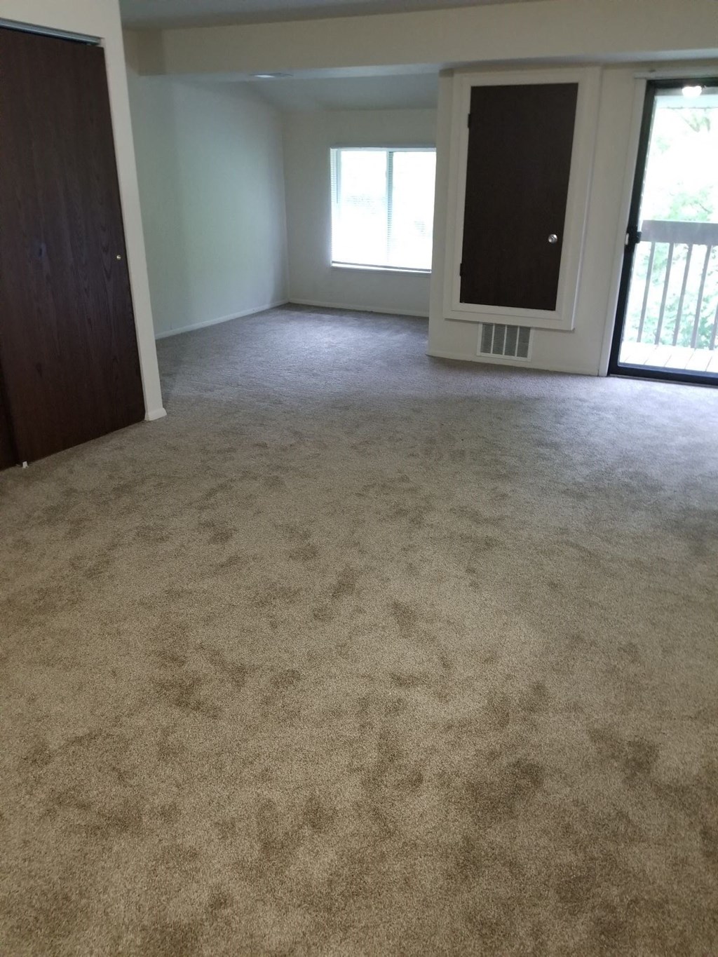 an empty living room with carpet and a door