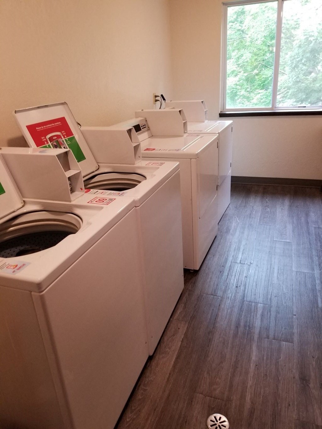 a row of washing machines in a room with wood floors