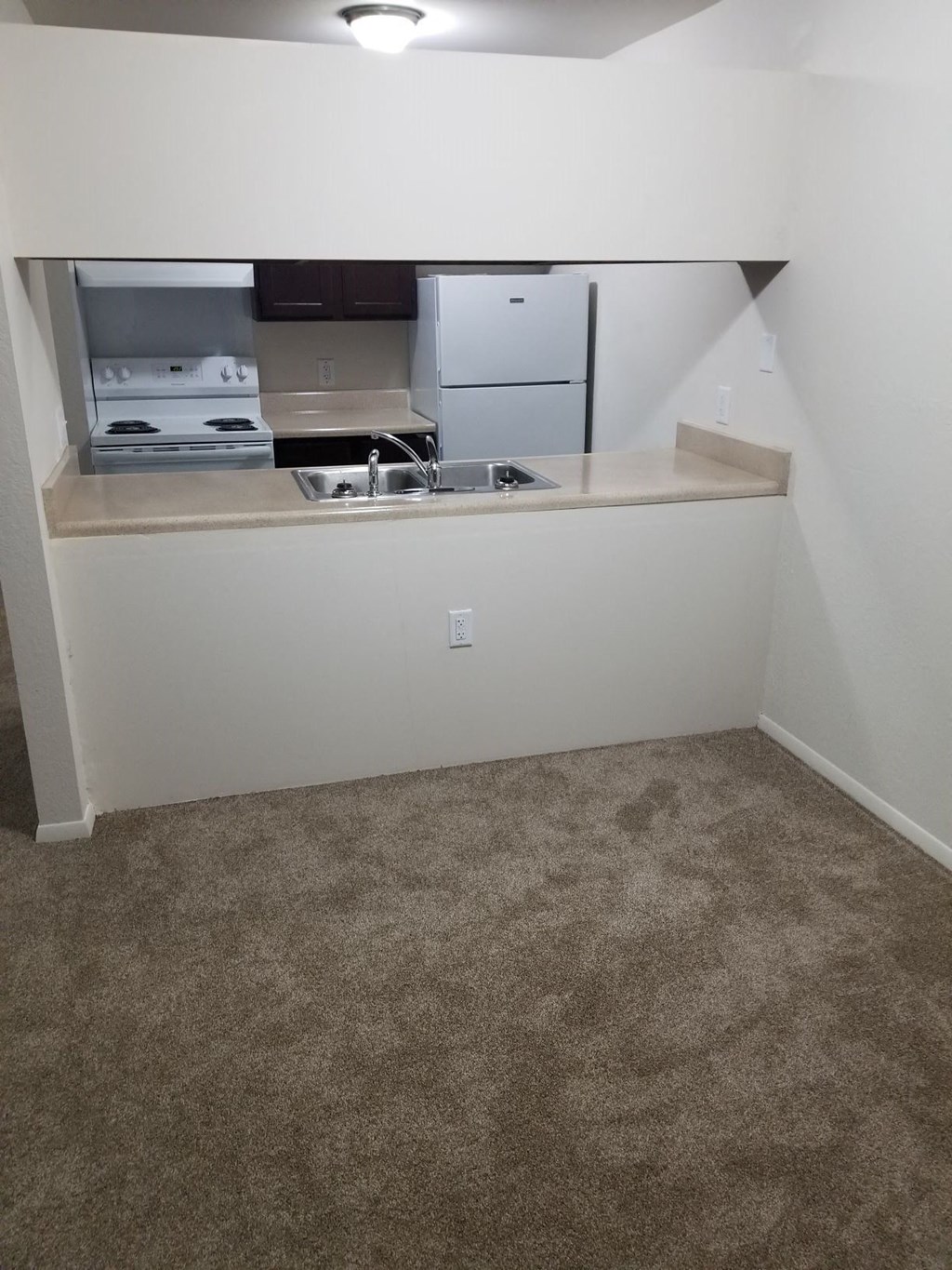 a kitchen with a sink and a refrigerator in a small room