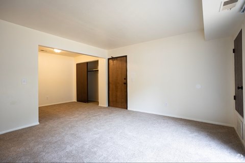 A room with a carpeted floor and two wooden doors.