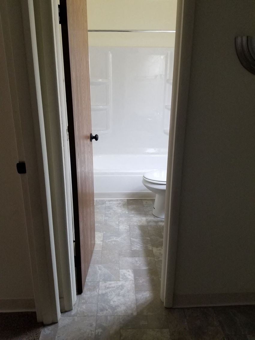 a bathroom with a toilet and a tub and a door open