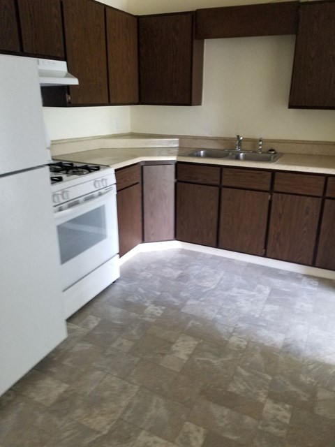 A kitchen with a white stove and brown cabinets.