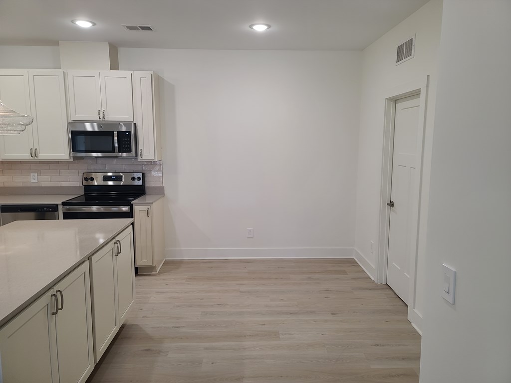 A kitchen with white cabinets and a black stove top oven.