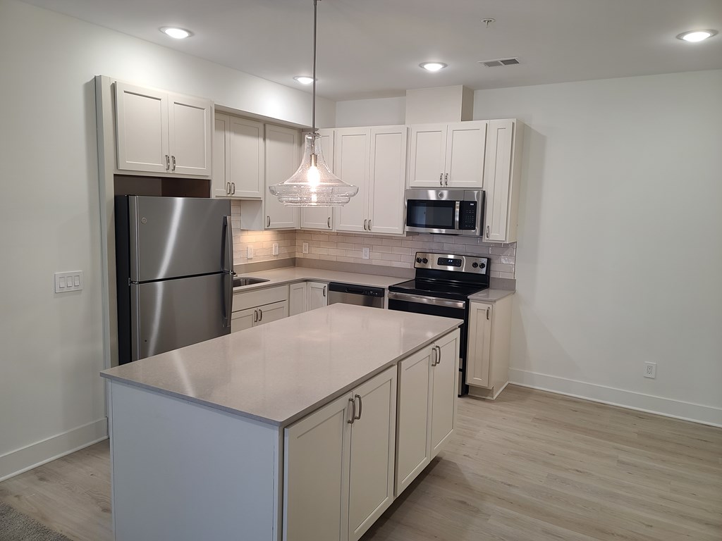 A kitchen with a stainless steel refrigerator, microwave, and oven.