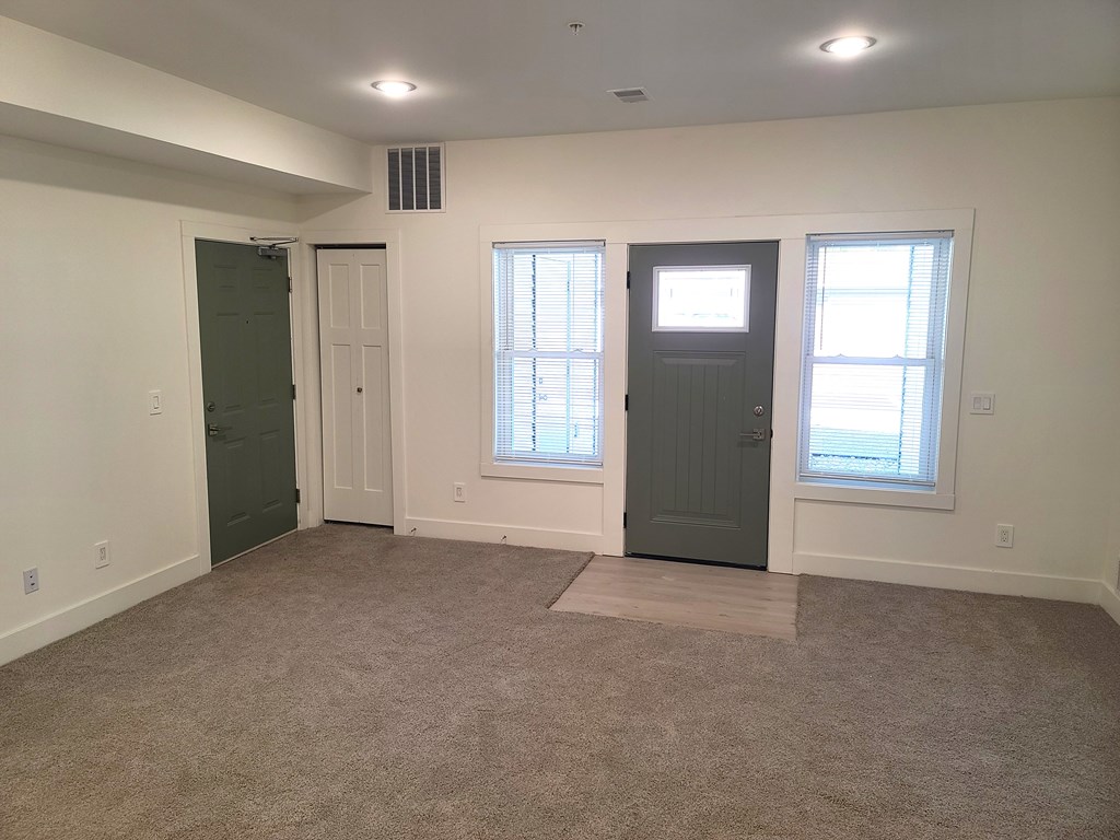 A room with a carpeted floor and two doors.