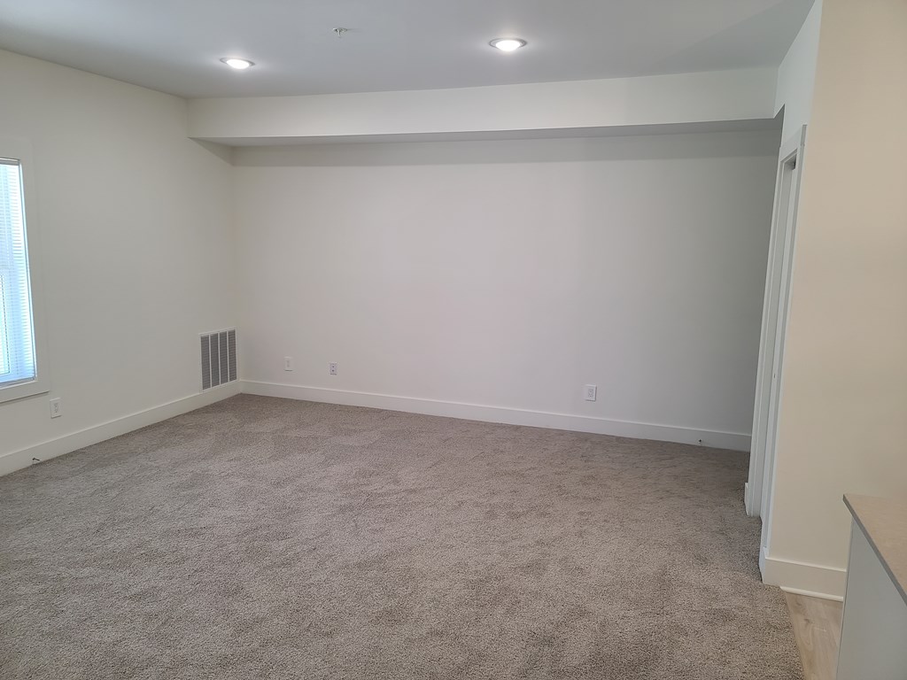 A large empty room with carpeted floor and white walls.