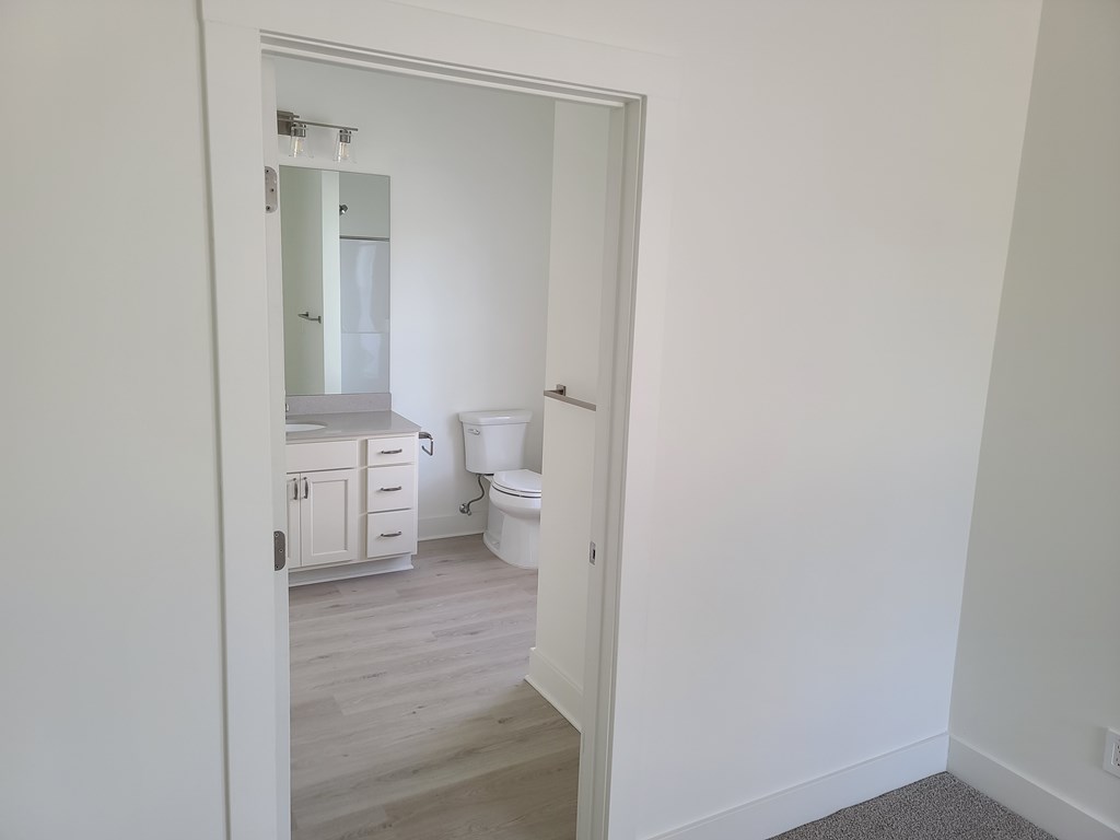 A white bathroom with a toilet, sink, and cabinet.