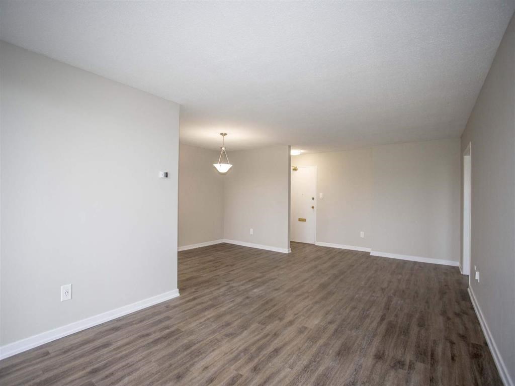 an empty living room with a wooden floor and white walls