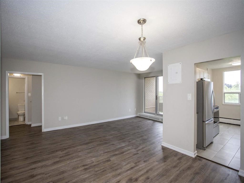 an empty kitchen and living room with a stainless steel refrigerator