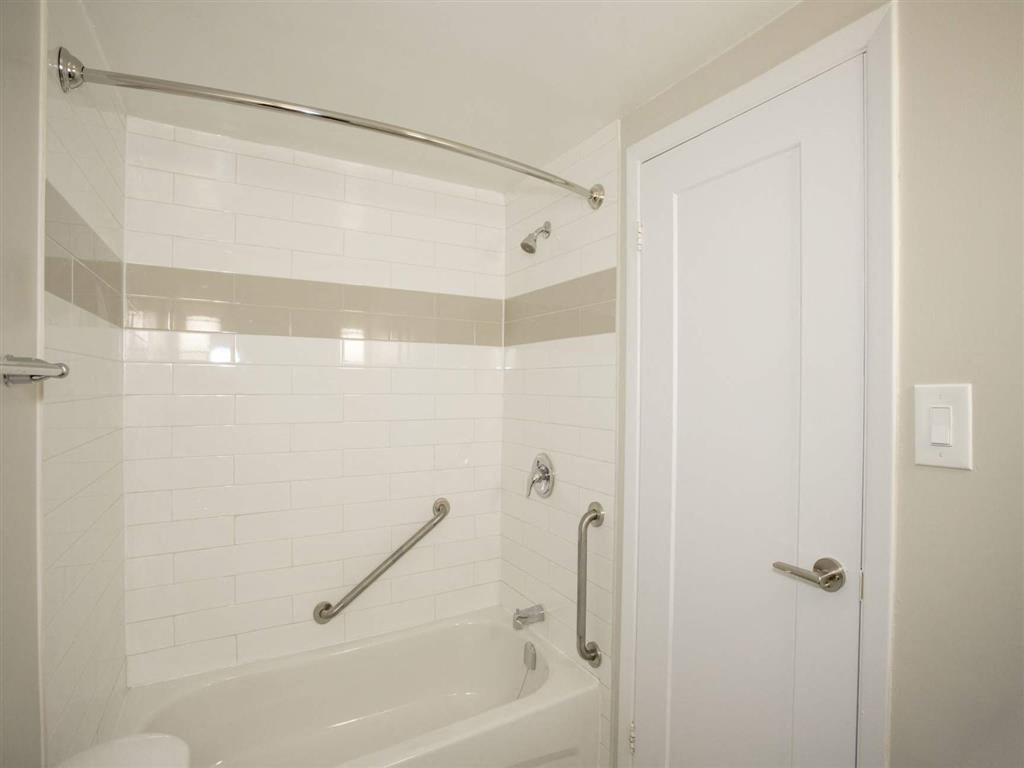 a white bathroom with a tub and a door