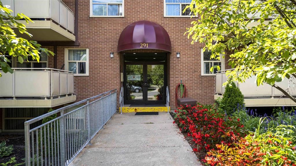 a sidewalk in front of a brick building with a glass door