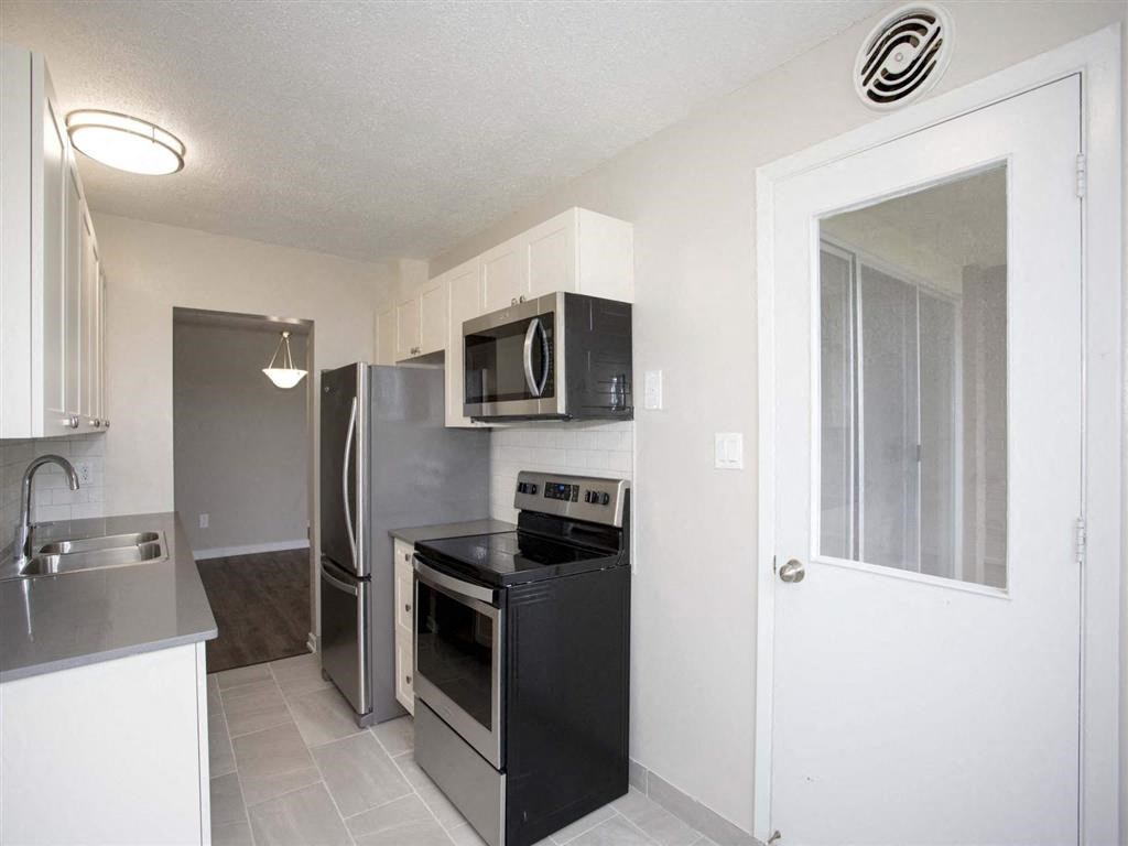 a kitchen with black appliances and a stainless steel refrigerator