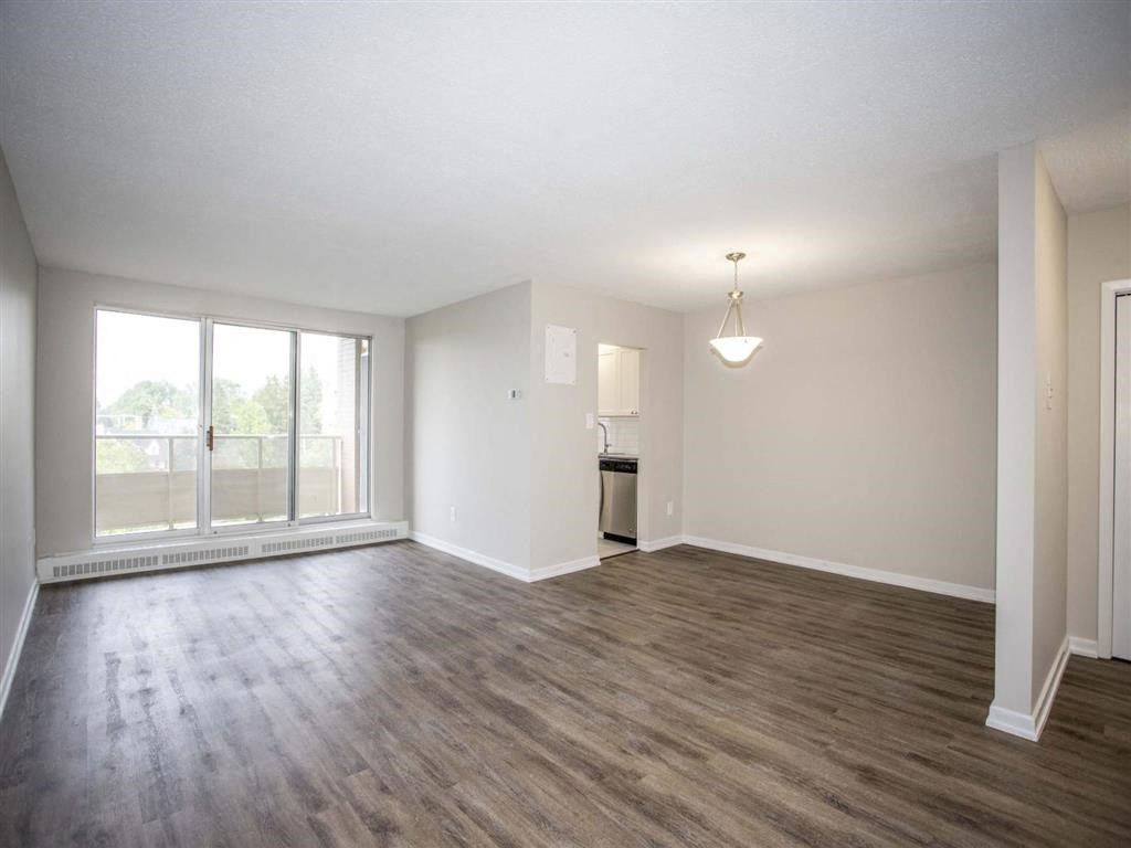 an empty living room with wood flooring and a window