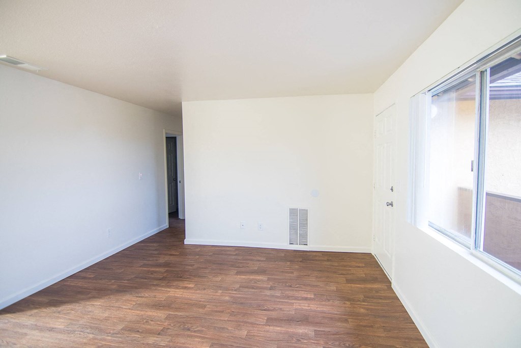 a living room with white walls and wood flooring and a large window