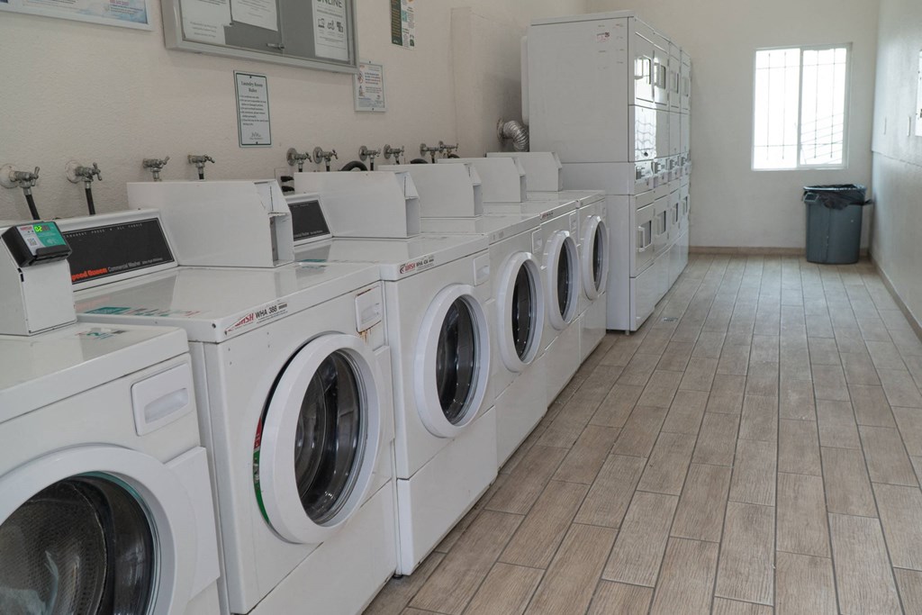 a row of washing machines and dryers in a laundry room