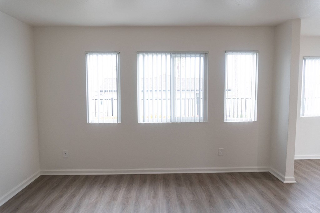 a living room with three windows and a wooden floor