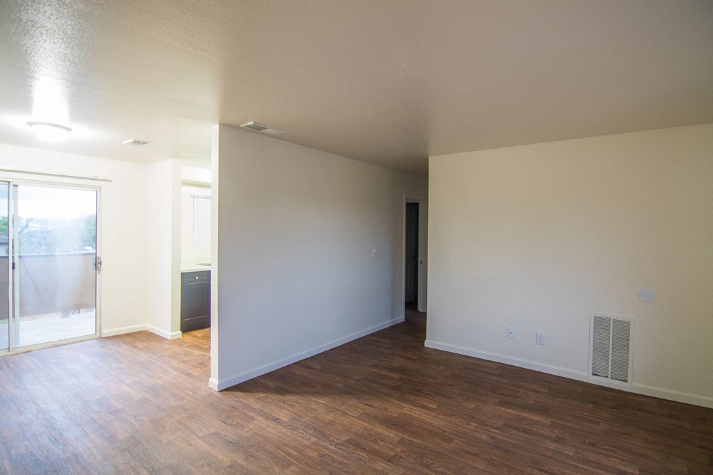 an empty living room with wood flooring and a sliding glass door