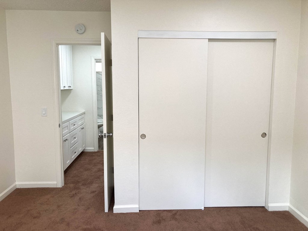 an empty bedroom with white closets and a carpeted floor at Casa Sol Apartments, Imperial Beach