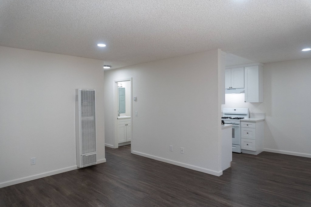 an empty living room and kitchen with white walls and wood flooring at Casa Sol Apartments, California