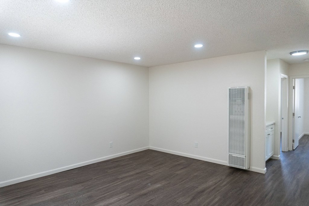 an empty living room with white walls and wood flooring at Casa Sol Apartments, Imperial Beach, CA