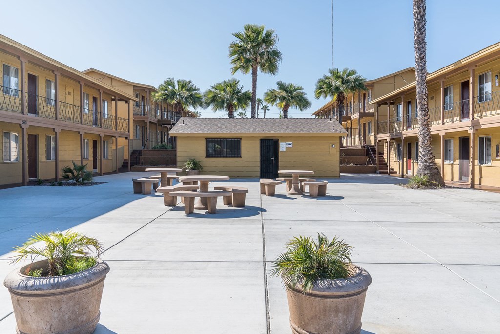 a courtyard with benches and palm trees in front of a building  at Casa Urbana Apartments, Chula Vista, California