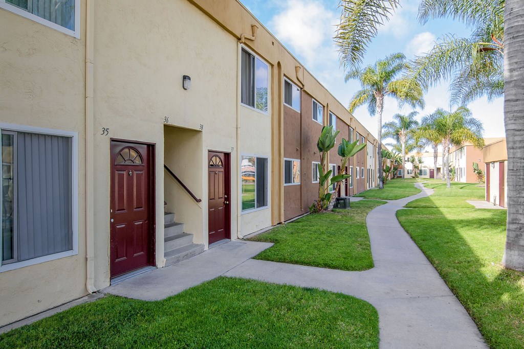 row of apartment buildings with a sidewalk and grass at Costa Fina Apartments, Chula Vista, CA, 91911