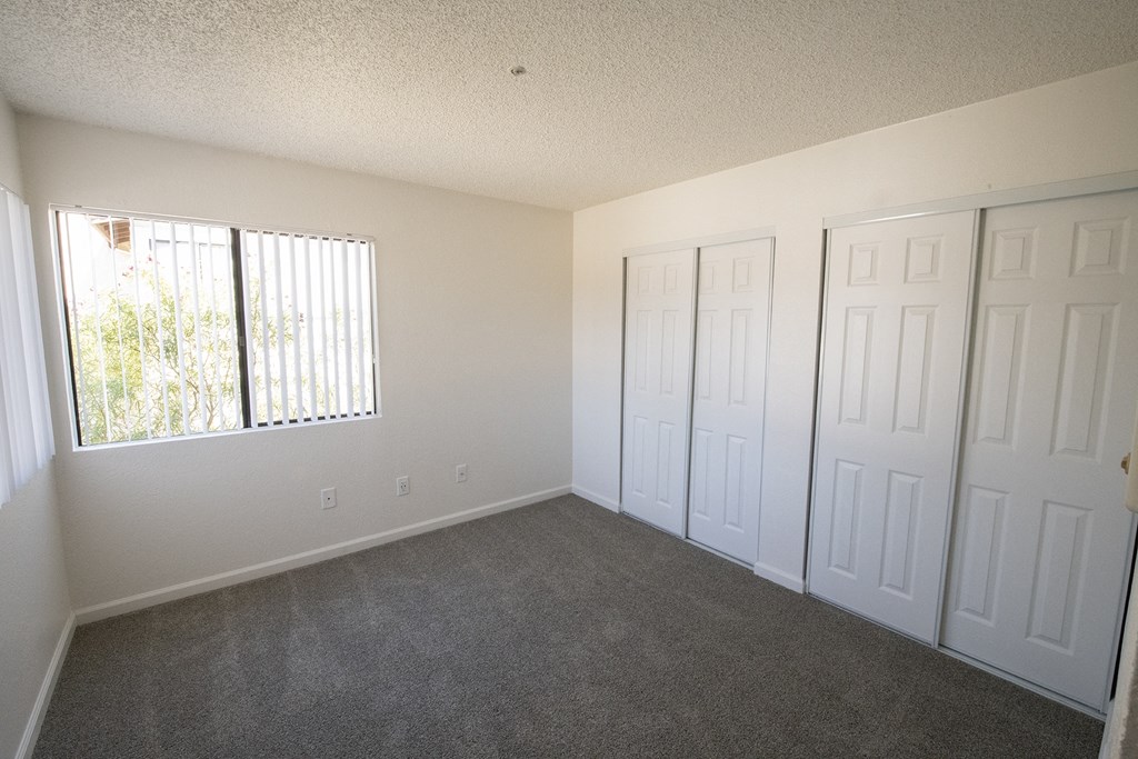 an empty bedroom with two closets and a window at Sycamore Hills Village Apartments, California, 92081