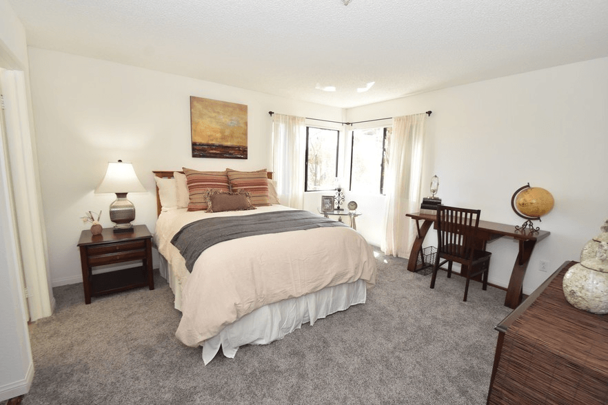 a bedroom with a bed and a desk and a window at Sycamore Hills Village Apartments, Vista, CA, 92081